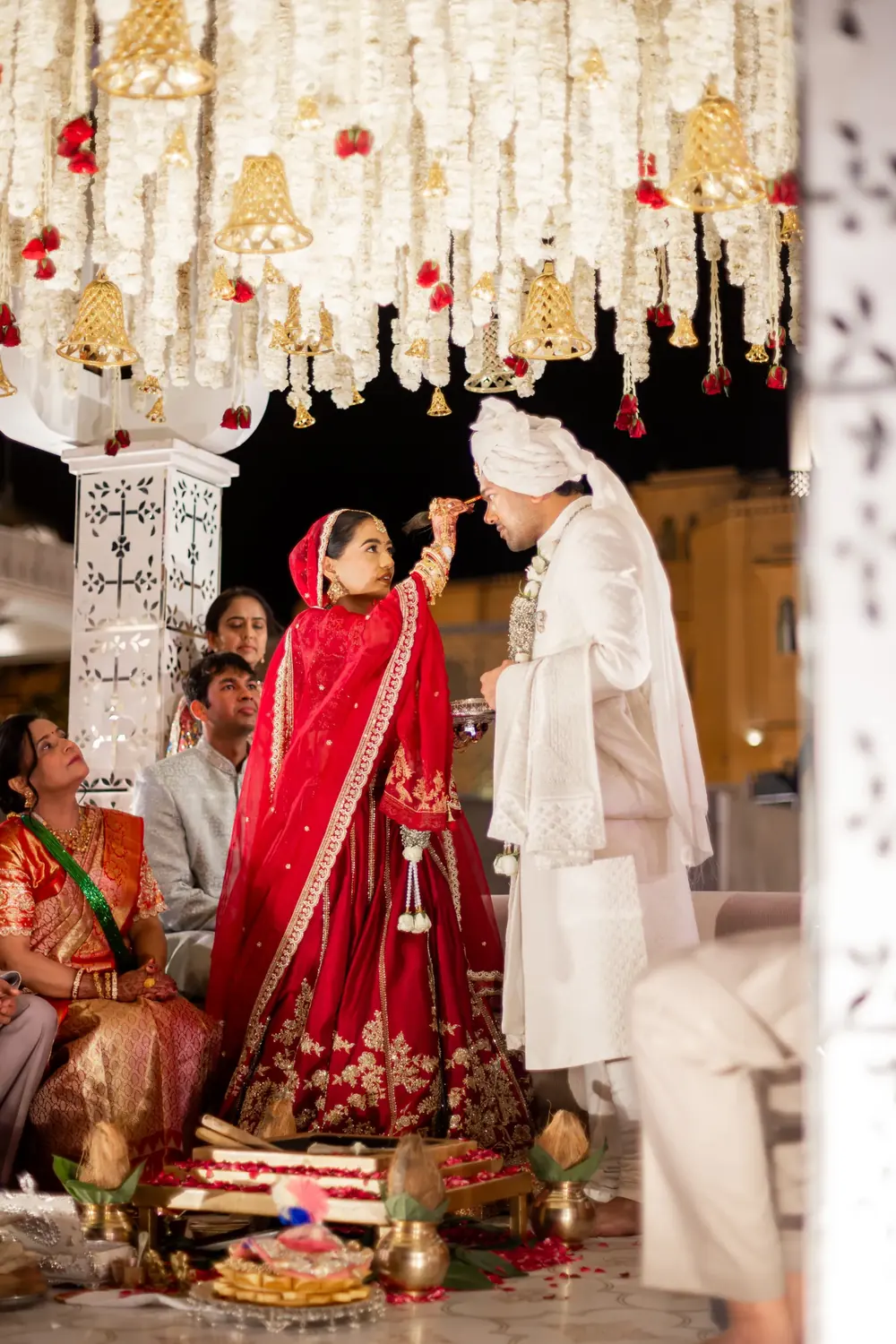 Bride and groom during their wedding rituals beneath hanging white floral strands