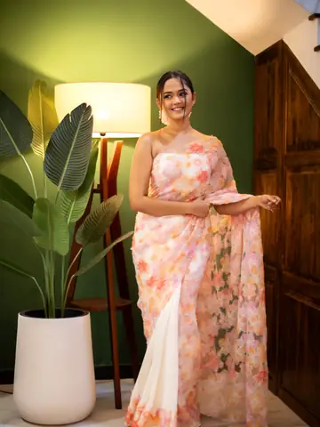 Model in a pink floral saree under warm lamp light