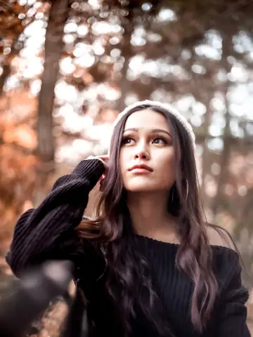 Woman in a knit sweater surrounded by autumn foliage