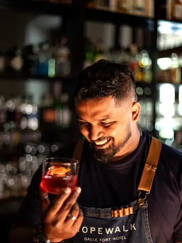 Smiling bartender holding up a cocktail glass
