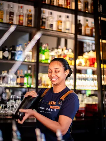 Bartender working at a bar lined with bottles