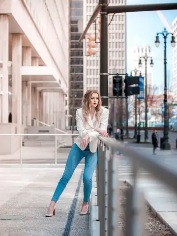 Woman in a white blazer posing in a bright city setting