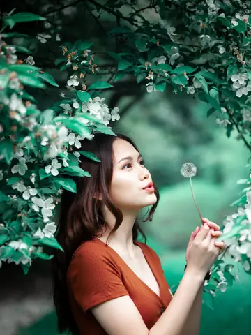 Young woman blowing a dandelion in a summer garden