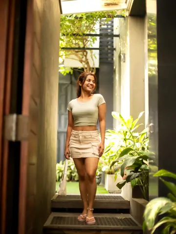 Model in a cropped top and skirt walking through a sunlit doorway