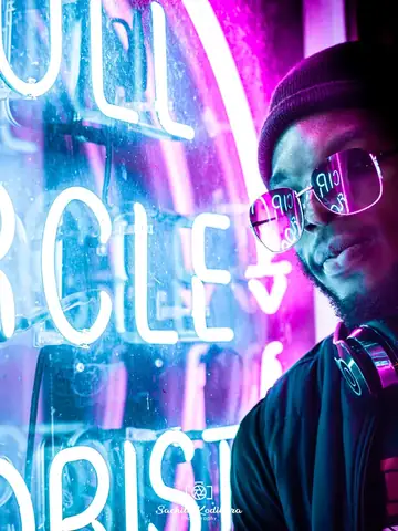 Man in a dark jacket and glasses under neon light