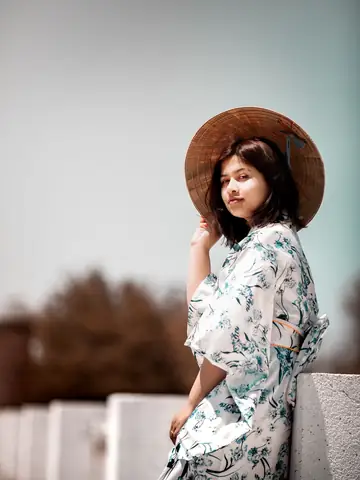 Woman in a floral kimono and conical hat outdoors