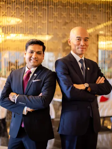 Two hotel executives in dark suits standing with arms crossed