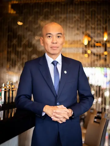 Executive portrait of a hotel leader in a navy suit in a warmly lit lobby