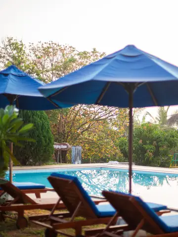 Pool deck with blue umbrellas and sun loungers in a tropical garden