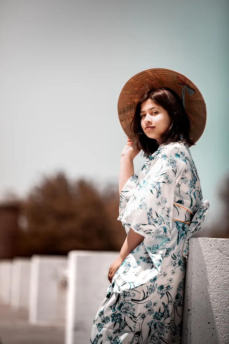 Woman in a floral kimono and conical hat outdoors