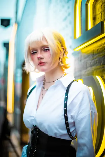 Close neon portrait of Ylva Brandt beside a glowing yellow sign