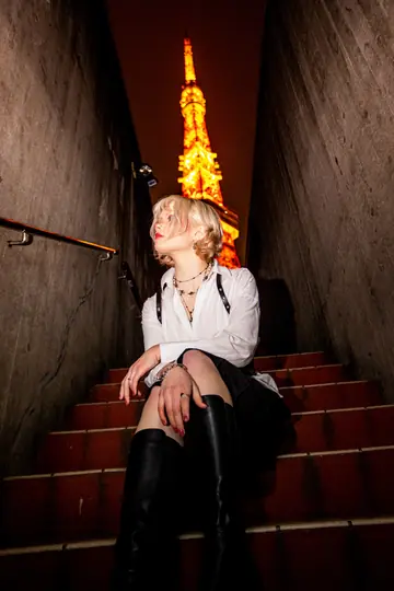 Ylva Brandt seated on red steps with Tokyo Tower glowing at the end of the passage