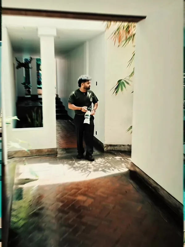 TikTok video cover: photographer in black with a camera in a white colonnaded courtyard