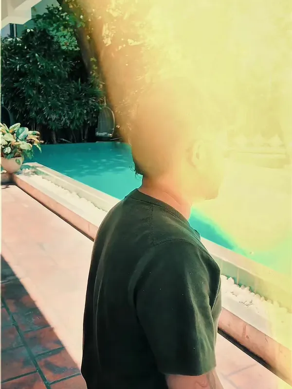 TikTok video cover: man in a green T-shirt by a hotel pool, washed in a warm light leak